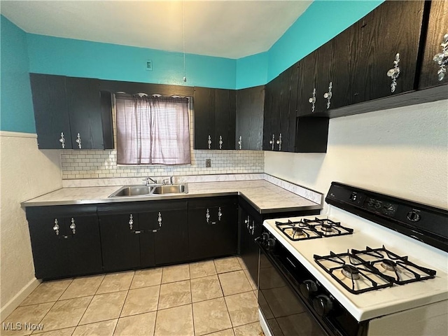 kitchen featuring backsplash, light countertops, a sink, and white gas stove