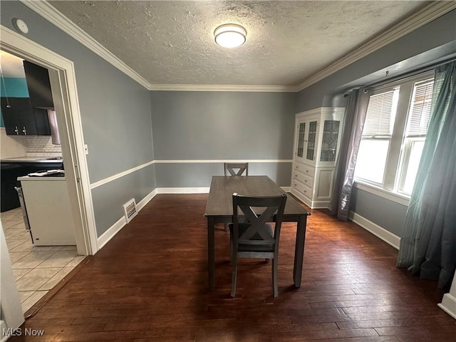 dining room featuring baseboards, visible vents, ornamental molding, hardwood / wood-style floors, and a textured ceiling