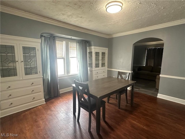 dining area featuring crown molding, a textured ceiling, arched walkways, and wood finished floors