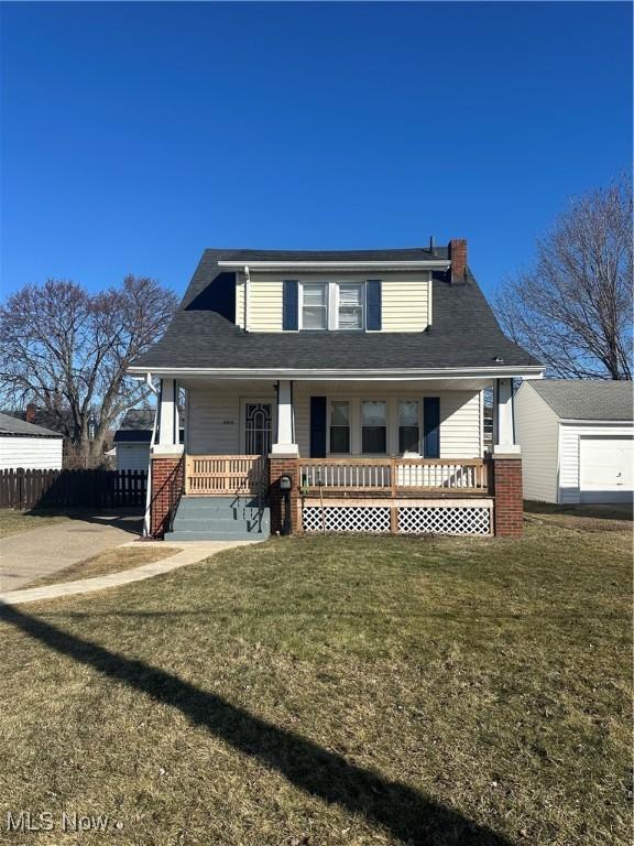 view of front facade featuring a front yard, covered porch, fence, and a chimney