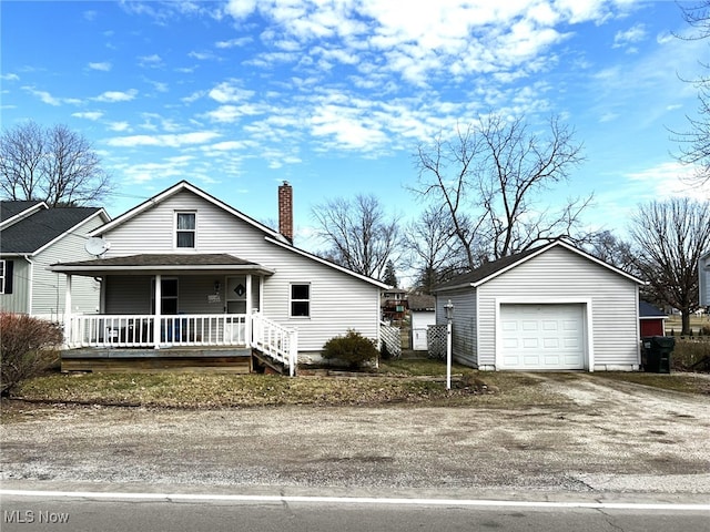 view of front of home with dirt driveway, a chimney, a detached garage, an outdoor structure, and a porch