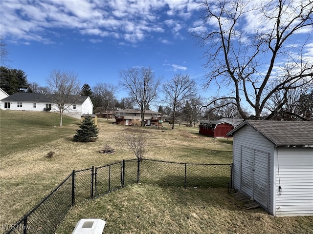 view of yard with a fenced backyard, a storage unit, and an outbuilding