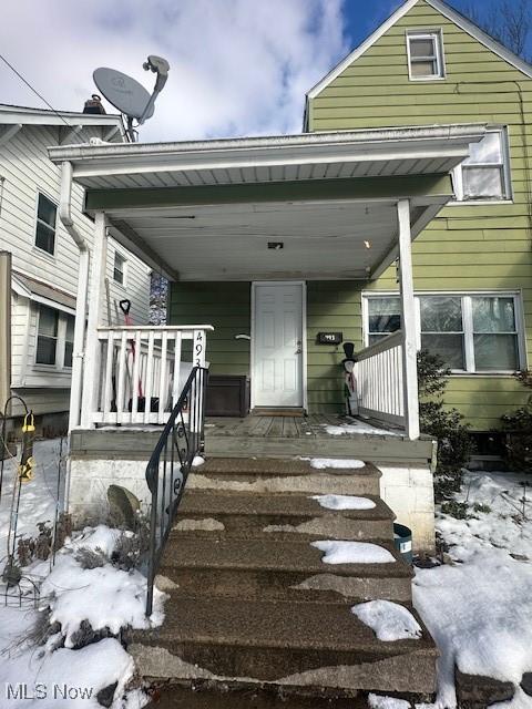 snow covered property entrance featuring a porch