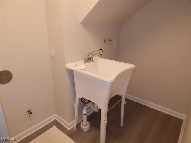 laundry room with baseboards and dark wood-type flooring