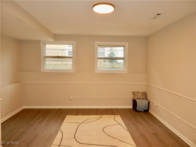 spare room with baseboards and wood finished floors