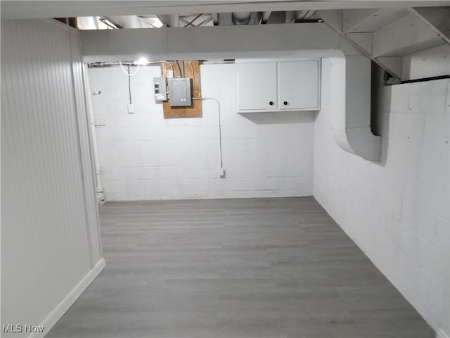 finished basement featuring wood finished floors, electric panel, and concrete block wall