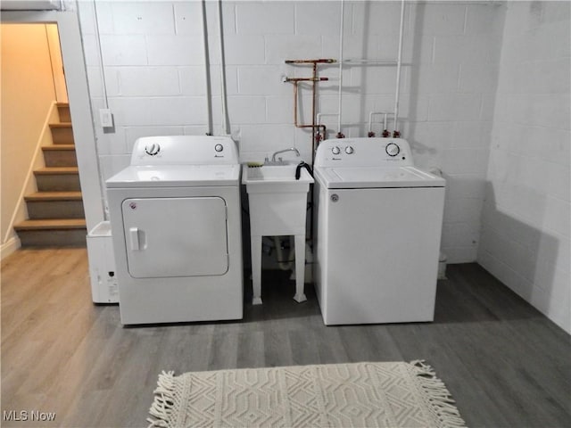 laundry area with wood finished floors, washing machine and dryer, and concrete block wall