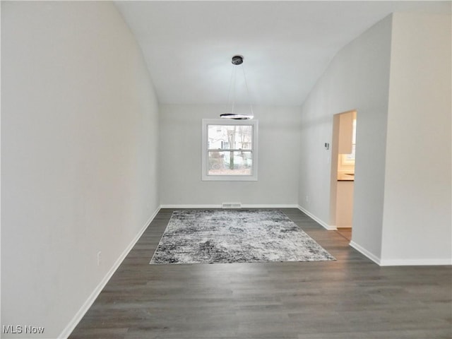 unfurnished dining area with dark wood-type flooring, lofted ceiling, visible vents, and baseboards