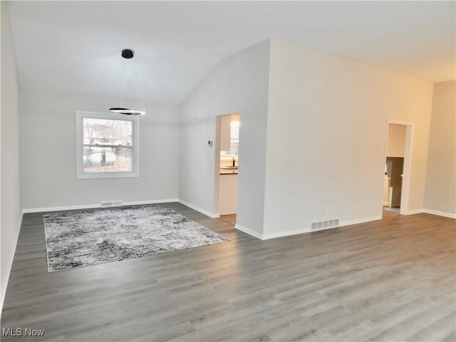 unfurnished room with lofted ceiling, wood finished floors, visible vents, and baseboards