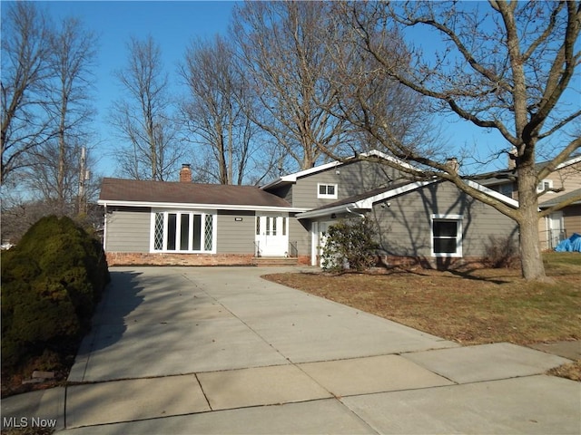 view of front facade with driveway and a chimney