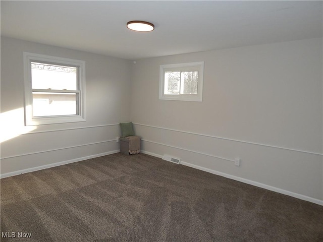 carpeted spare room with baseboards, visible vents, and a wealth of natural light