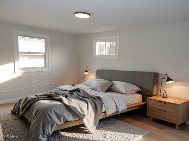 bedroom with light wood finished floors and multiple windows