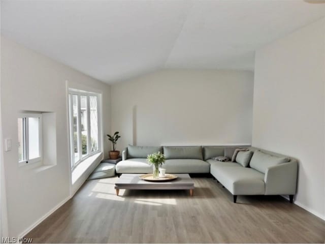 living area with lofted ceiling, wood finished floors, and baseboards