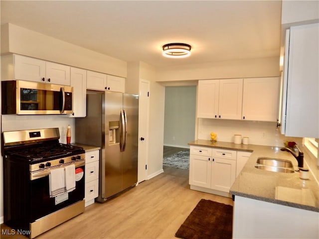 kitchen with stone counters, white cabinetry, appliances with stainless steel finishes, and a sink