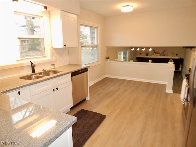 kitchen featuring stainless steel dishwasher, a sink, light wood-style floors, and white cabinets