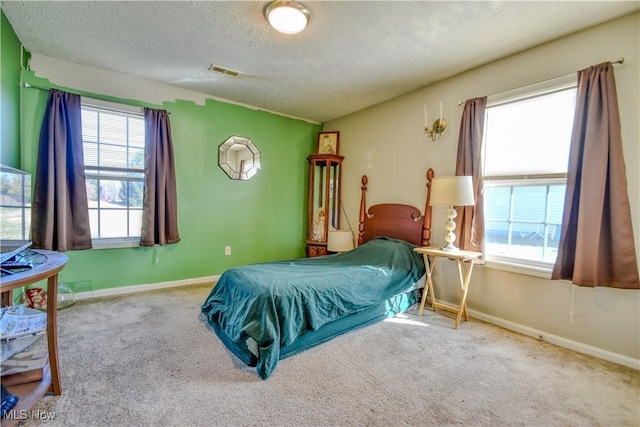 bedroom with a textured ceiling, carpet, visible vents, and baseboards