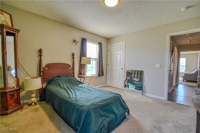 carpeted bedroom with multiple windows, baseboards, and a textured ceiling