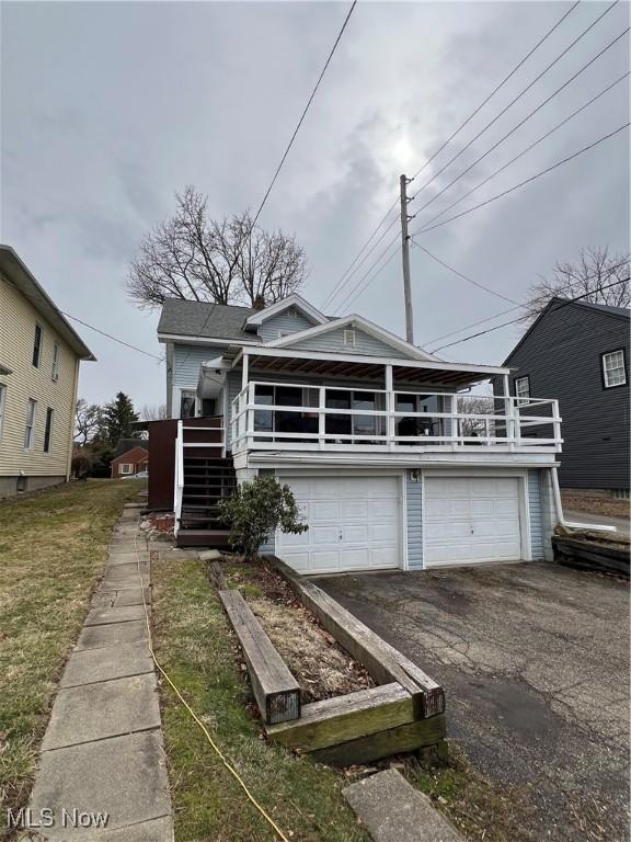 view of front facade with a garage, aphalt driveway, and stairs