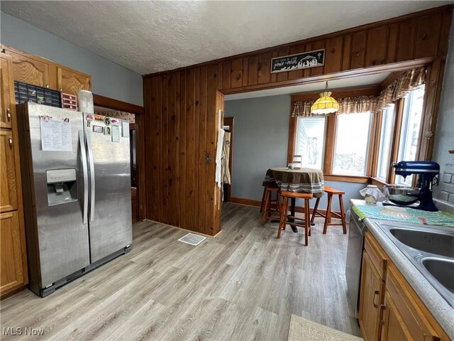 kitchen with a textured ceiling, a sink, visible vents, appliances with stainless steel finishes, and light wood finished floors