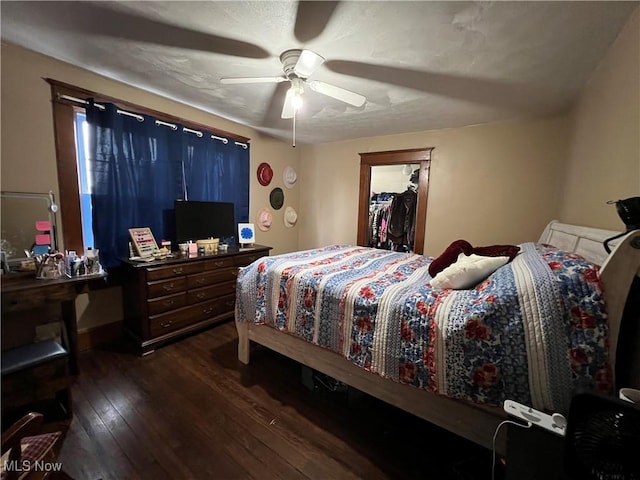 bedroom with a closet, dark wood finished floors, a ceiling fan, and a walk in closet