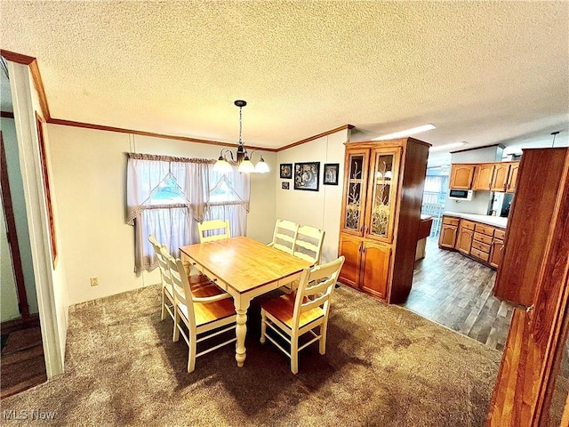 dining space featuring a textured ceiling, dark colored carpet, an inviting chandelier, and crown molding
