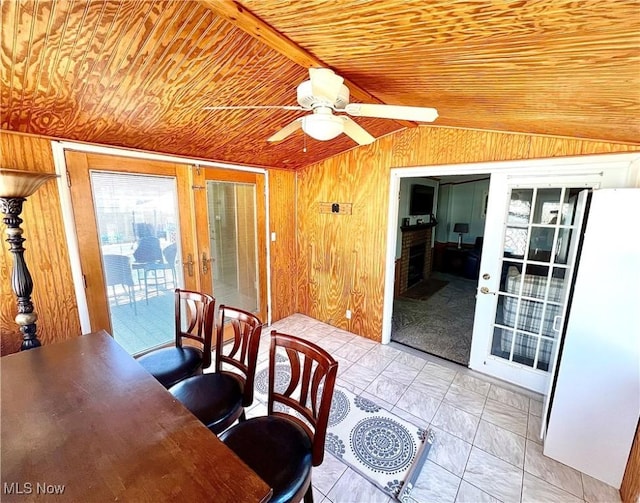 dining area with lofted ceiling, ceiling fan, wooden ceiling, wooden walls, and french doors
