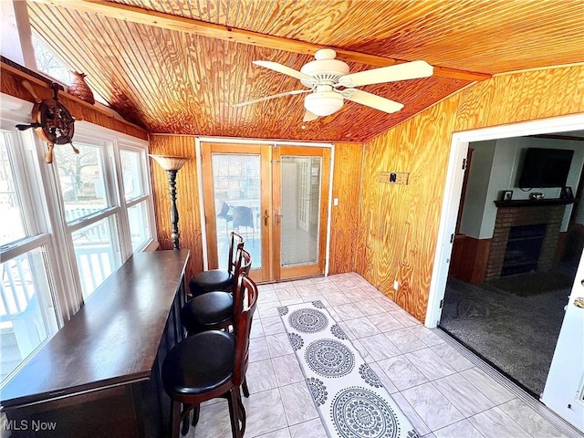 sunroom with lofted ceiling, ceiling fan, wooden ceiling, and a fireplace