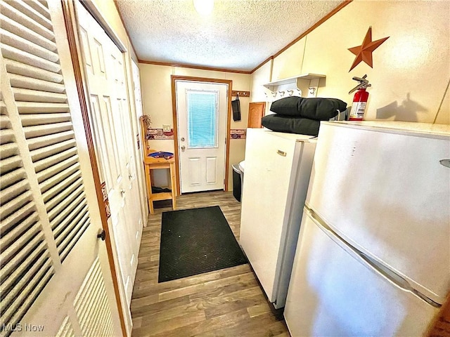 kitchen with a textured ceiling, ornamental molding, wood finished floors, and freestanding refrigerator