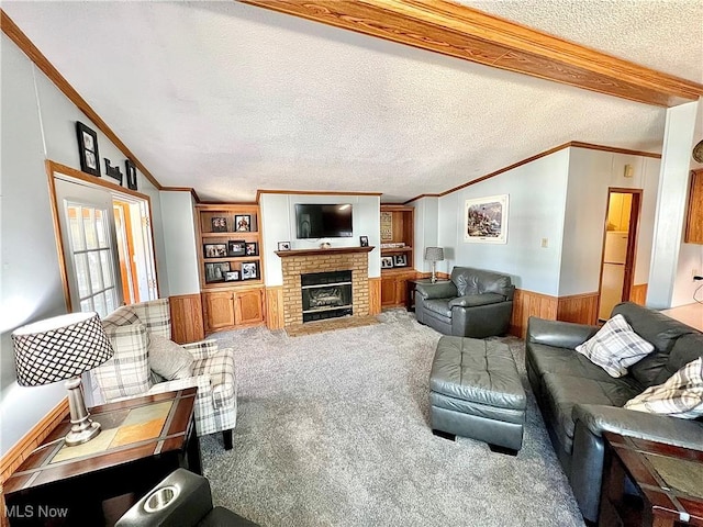 carpeted living area with lofted ceiling, ornamental molding, wainscoting, wood walls, and a textured ceiling
