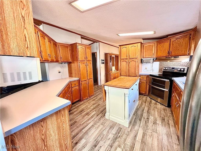 kitchen featuring appliances with stainless steel finishes, brown cabinetry, under cabinet range hood, and light wood finished floors
