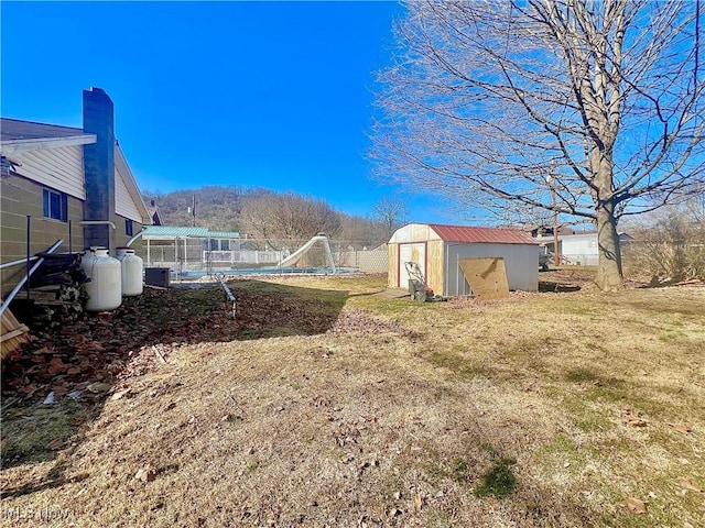 view of yard featuring an outbuilding, fence, and a storage shed