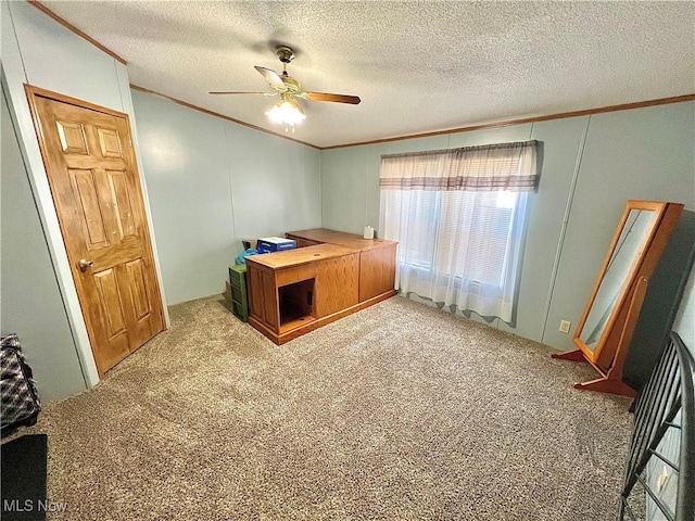 carpeted office space featuring a textured ceiling, a ceiling fan, and crown molding