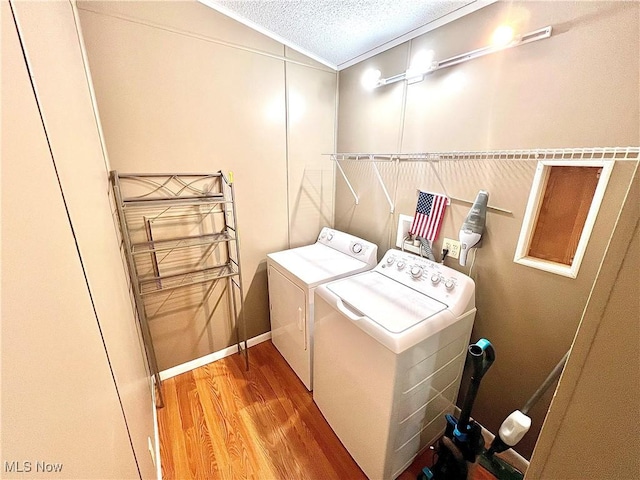 clothes washing area featuring ornamental molding, a textured ceiling, wood finished floors, laundry area, and independent washer and dryer