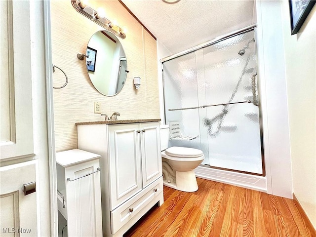 bathroom featuring a textured ceiling, a stall shower, wood finished floors, and vanity