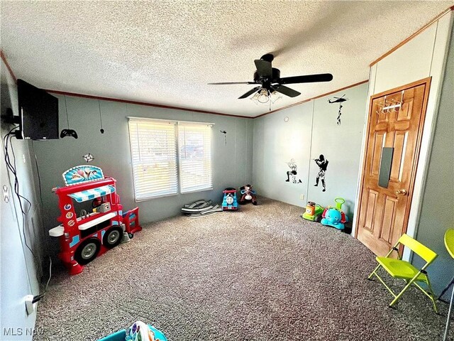 rec room with ornamental molding, carpet flooring, ceiling fan, and a textured ceiling