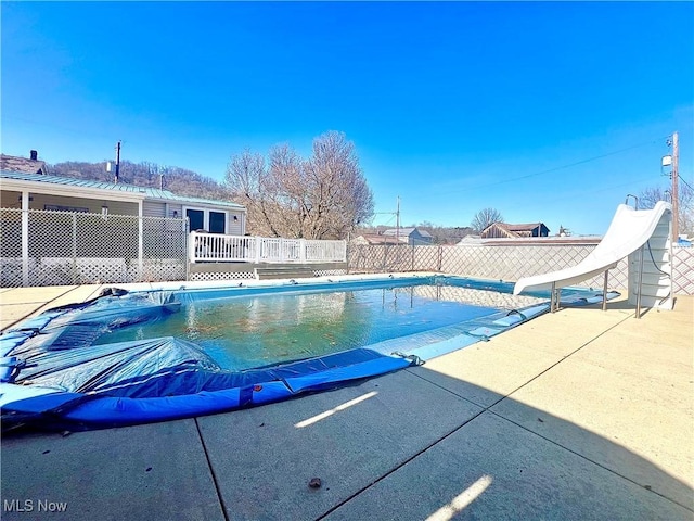 view of pool with a fenced in pool, a patio, fence, a deck, and a water slide