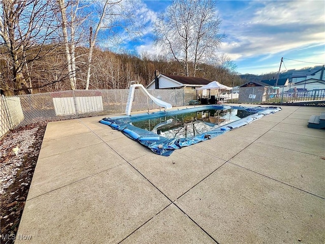 view of pool with a patio area, a fenced backyard, a fenced in pool, and a water slide