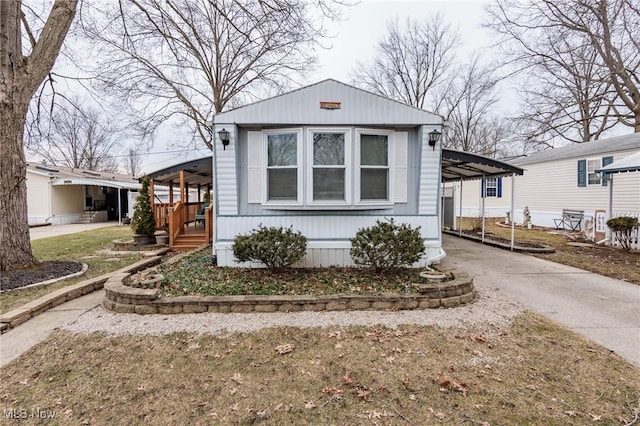 manufactured / mobile home with concrete driveway and an attached carport