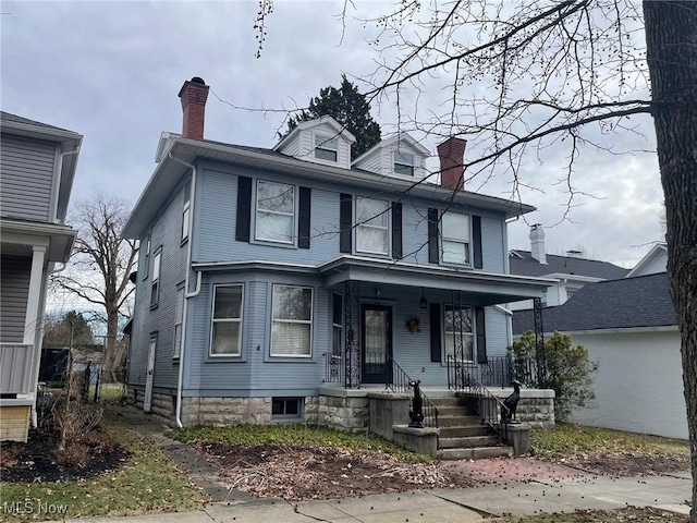 traditional style home featuring covered porch and a chimney