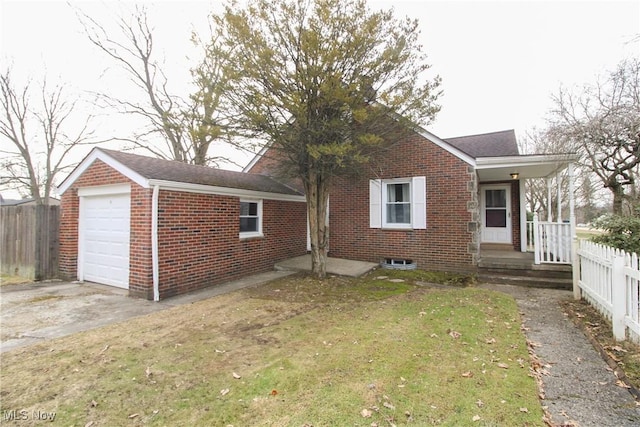 exterior space with a garage, brick siding, a front yard, and fence