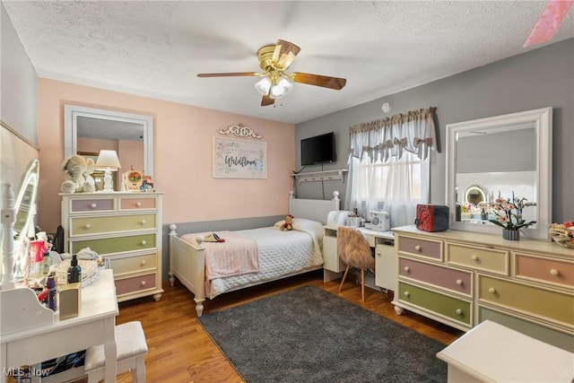 bedroom with ceiling fan, a textured ceiling, and wood finished floors