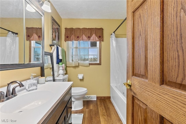 full bath with a textured ceiling, toilet, wood finished floors, vanity, and visible vents