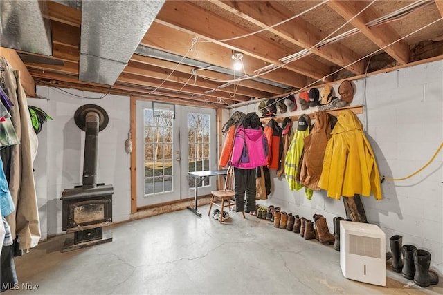 mudroom featuring concrete flooring, a wood stove, and french doors