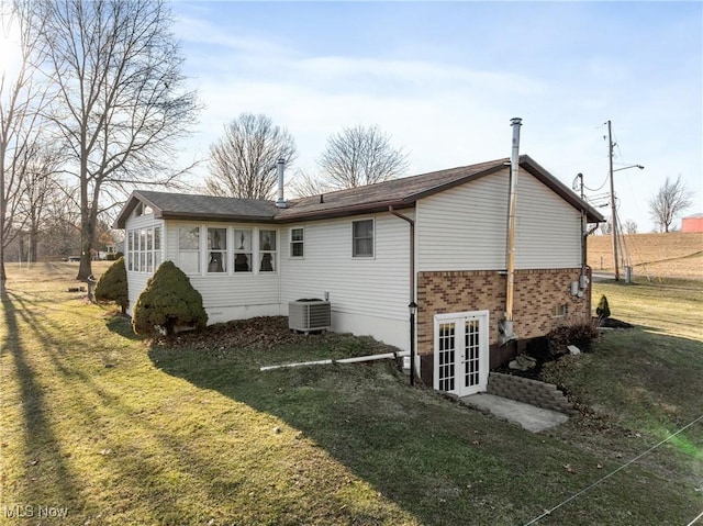 back of house with brick siding, a yard, central AC unit, and french doors