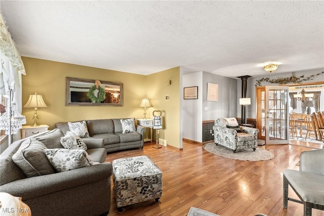 living area with a notable chandelier, a textured ceiling, and wood finished floors