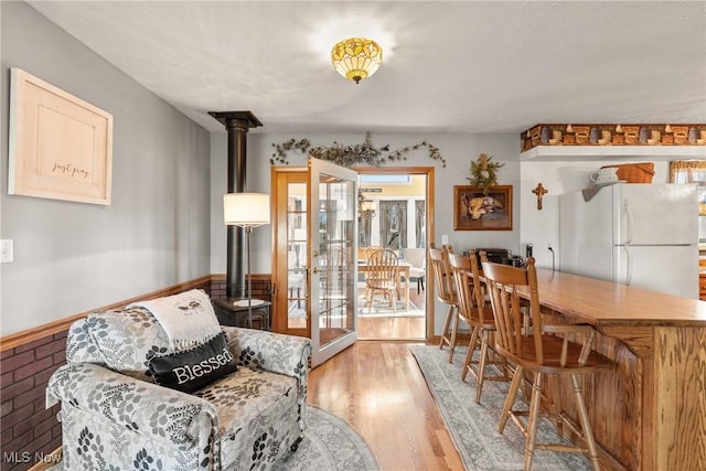 dining space featuring light wood-type flooring, a wood stove, and baseboards