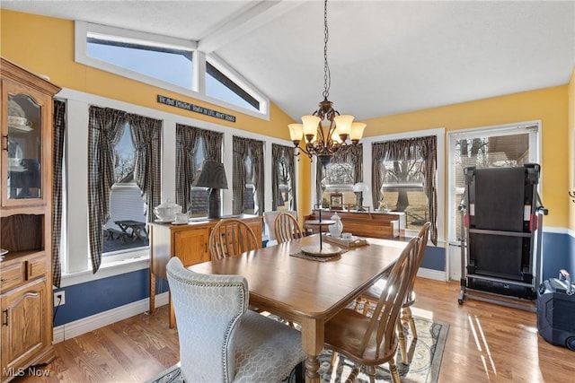 dining room featuring vaulted ceiling with beams, light wood finished floors, a wealth of natural light, and an inviting chandelier