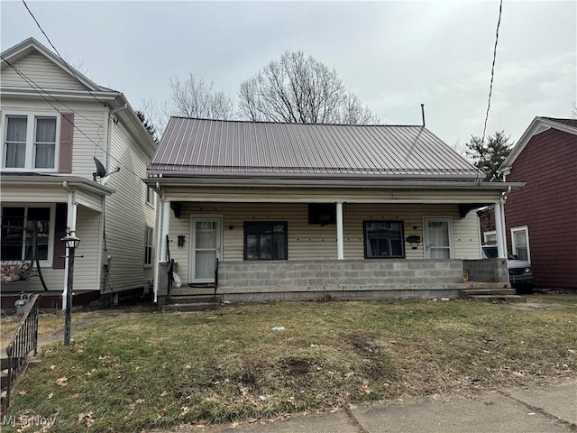 view of front of home with covered porch, metal roof, and a front lawn