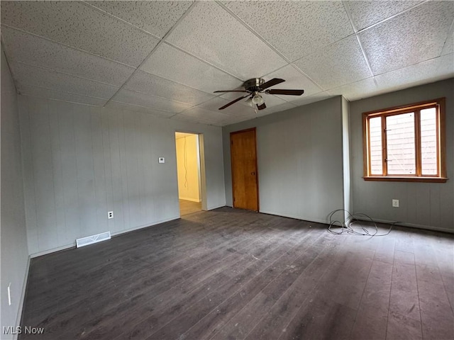 spare room with ceiling fan, visible vents, dark wood finished floors, and a drop ceiling