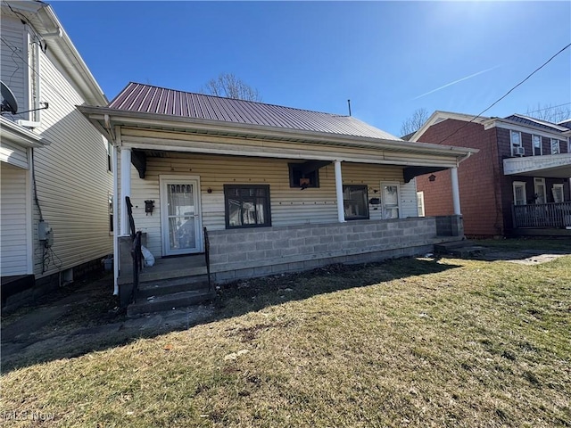 view of front of house with covered porch, a front lawn, and metal roof